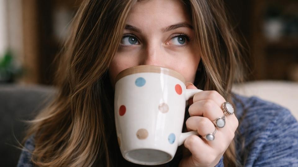 Does Caffeine Make Anxiety Worse In short, yes, a woman thinks while drinking from her mug.