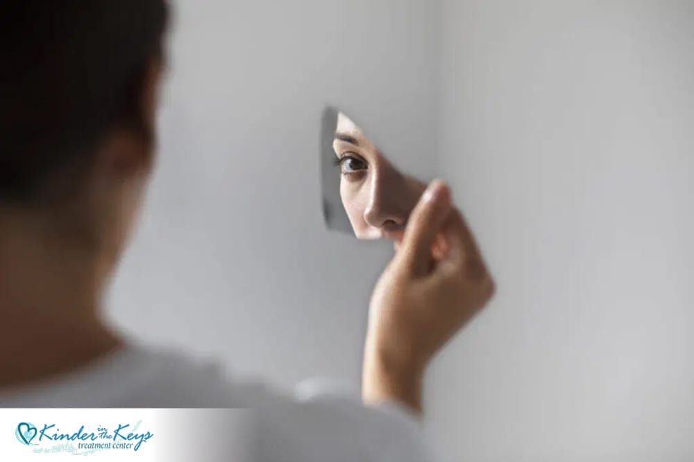 Woman holding her head in distress, sitting indoors, symbolizing emotional struggles often linked to narcissistic abuse symptoms.