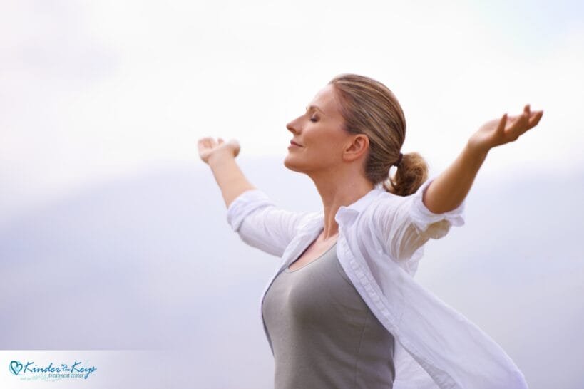 Woman lifting hands while enjoying calming spring breeze