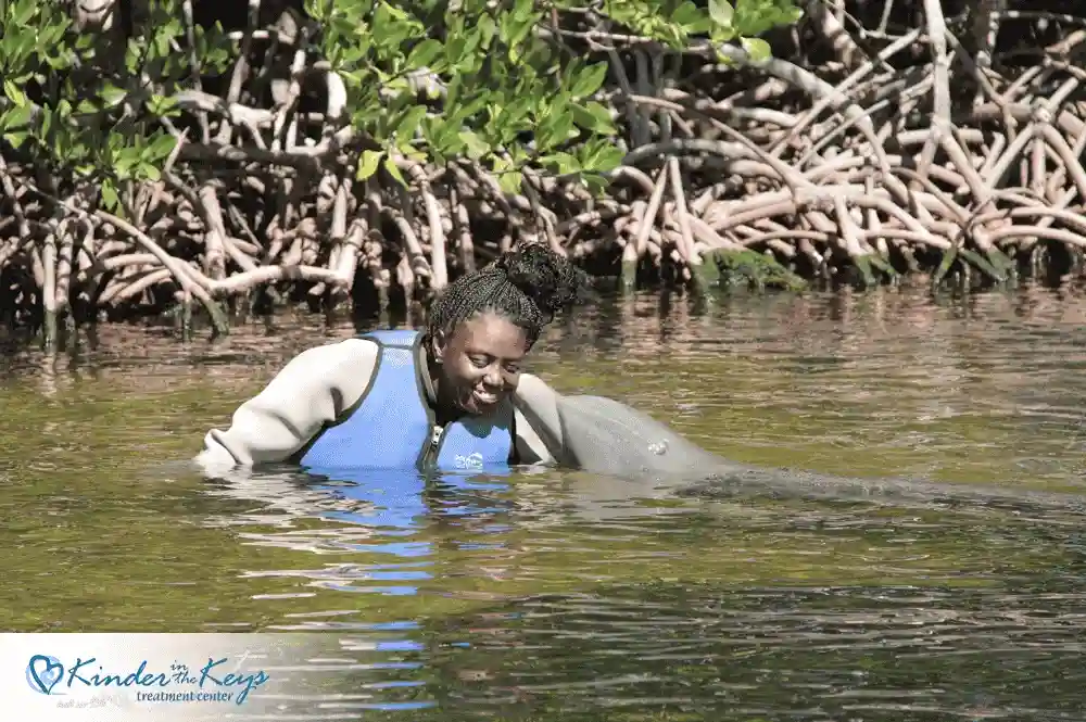 Woman interacting with dolphin as part of therapy
