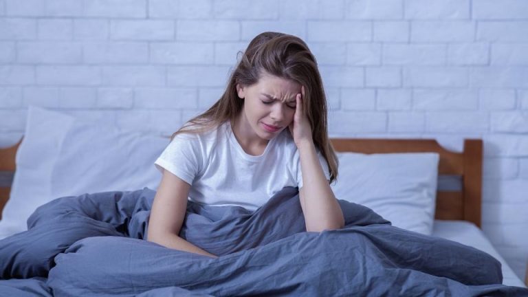 CPTSD vs. BPD hero image of a woman dealing with mental health disorders in bed.