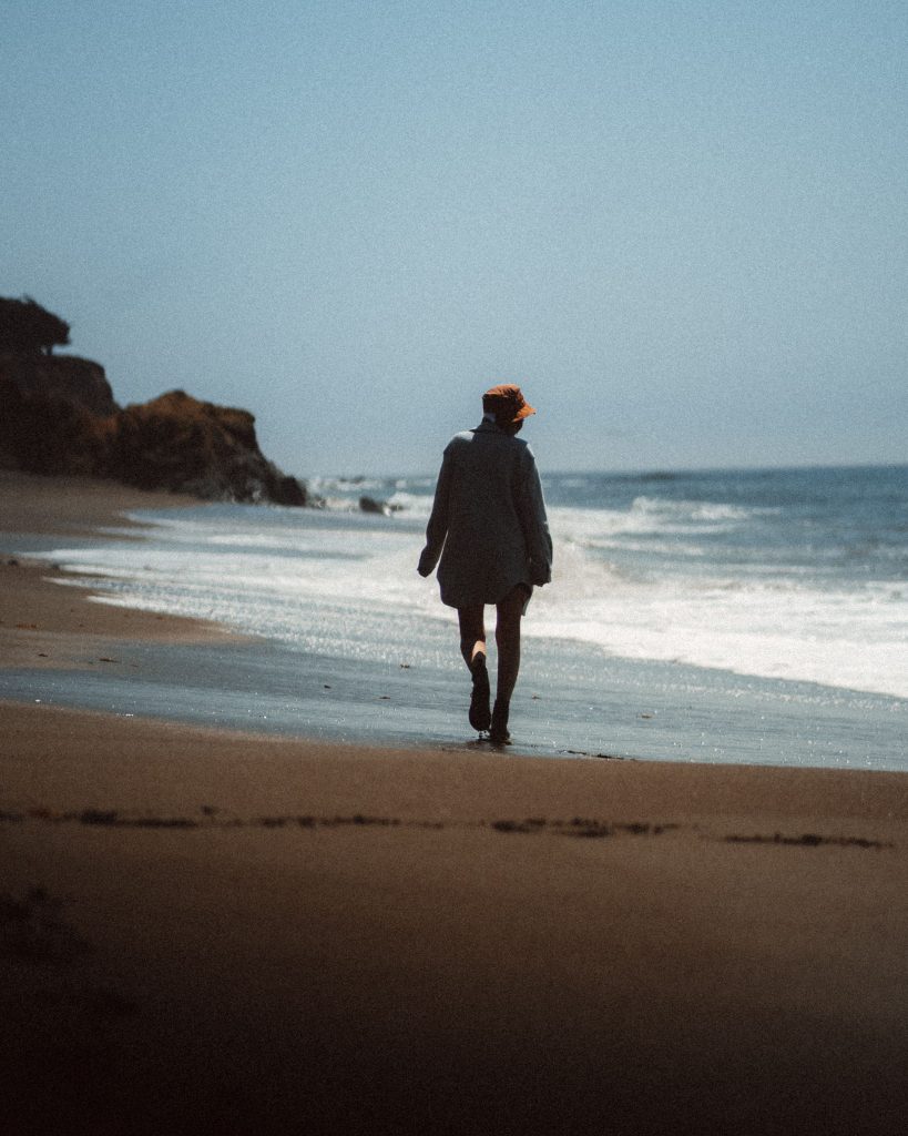 A woman walking peacefully along the shoreline during narcissistic abuse recovery for women