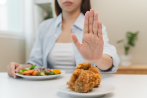 woman pushing away bad food and eating good food